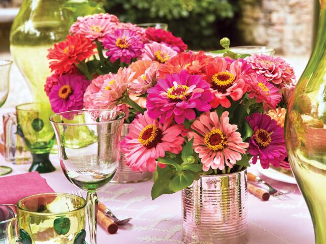 Bright pink zinnias contrast with lime green colored glassware on a bubblegum pink tablecloth.