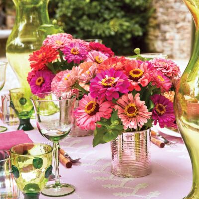 Bright pink zinnias contrast with lime green colored glassware on a bubblegum pink tablecloth.