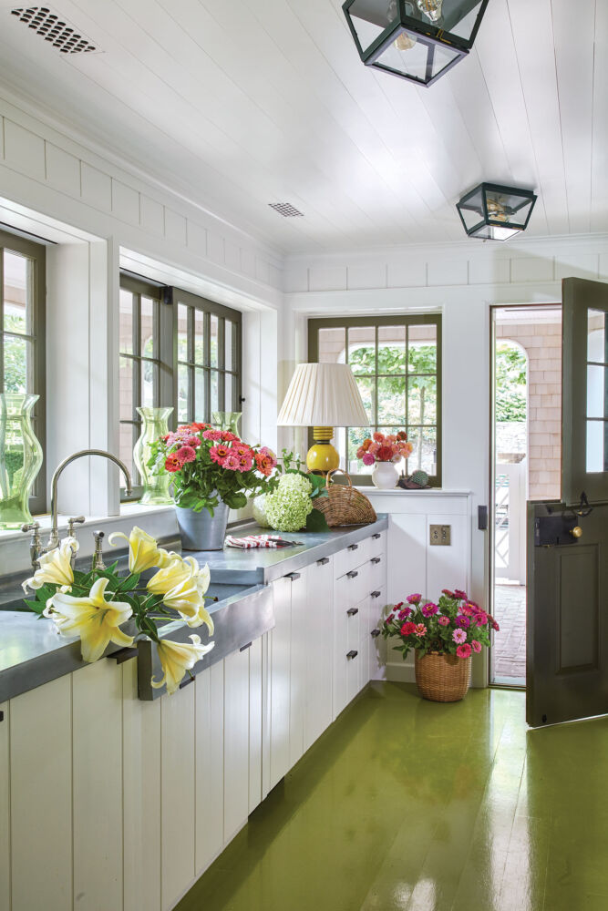 A white kitchen overflows with flowers ready to be arranged.