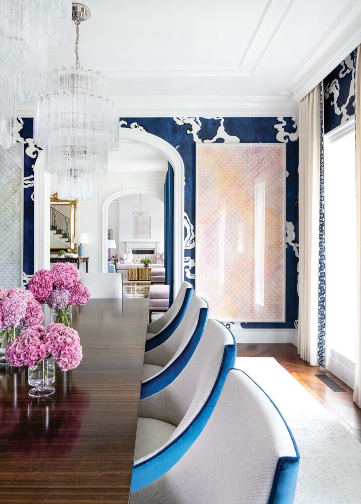 A deep blue marbled wallpaper envelopes a high ceilinged dining room.