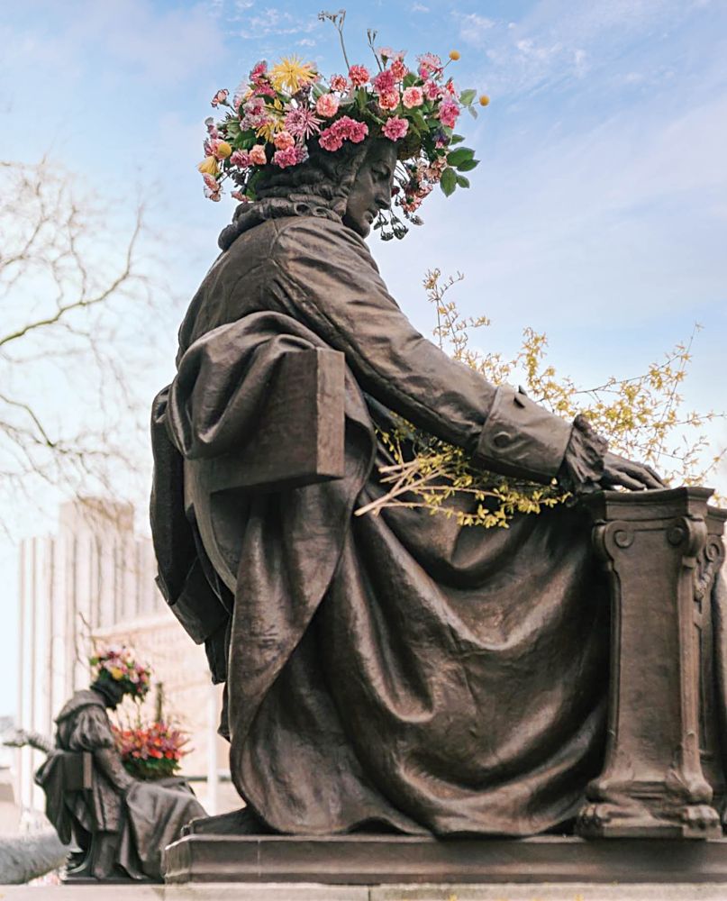 Floral wreaths sit on the heads of statues.