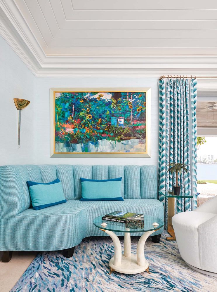 A turquoise blue couch matches pillows, the rug, and curtains in a formal living room.