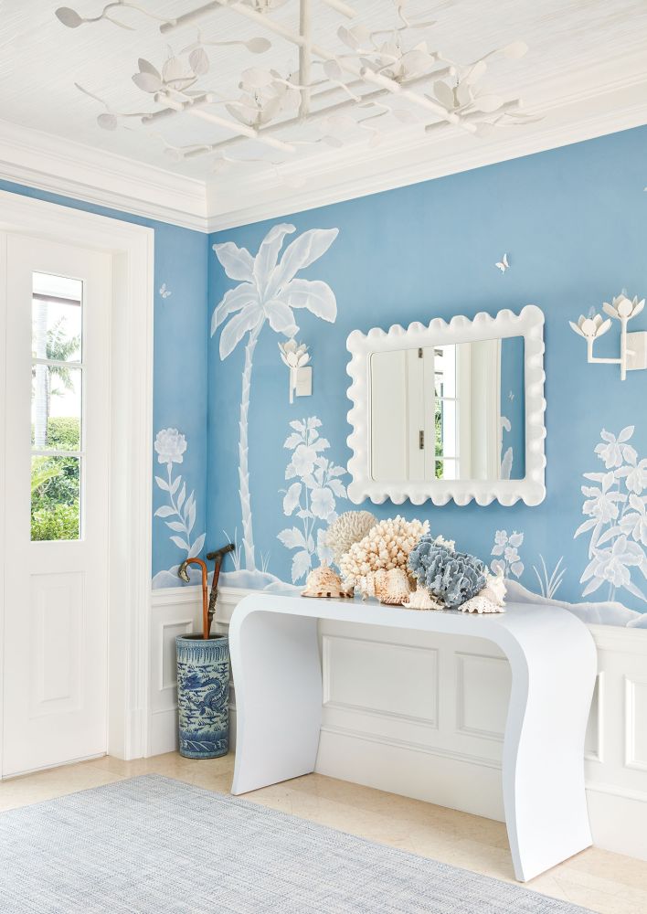 A blue coastal wallpaper wraps around an entryway with shells.