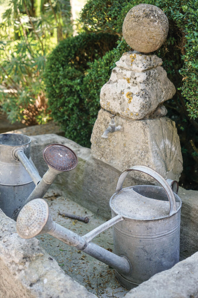 Two watering cans sit in a stone trough.