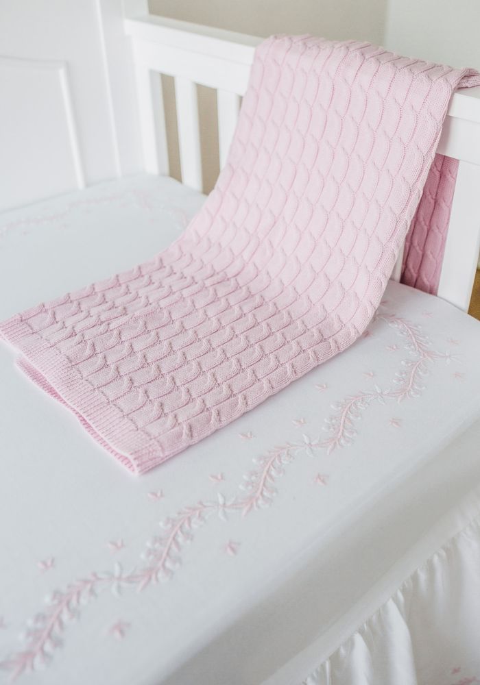 Pink embroidered crib sheet with pink blanket.