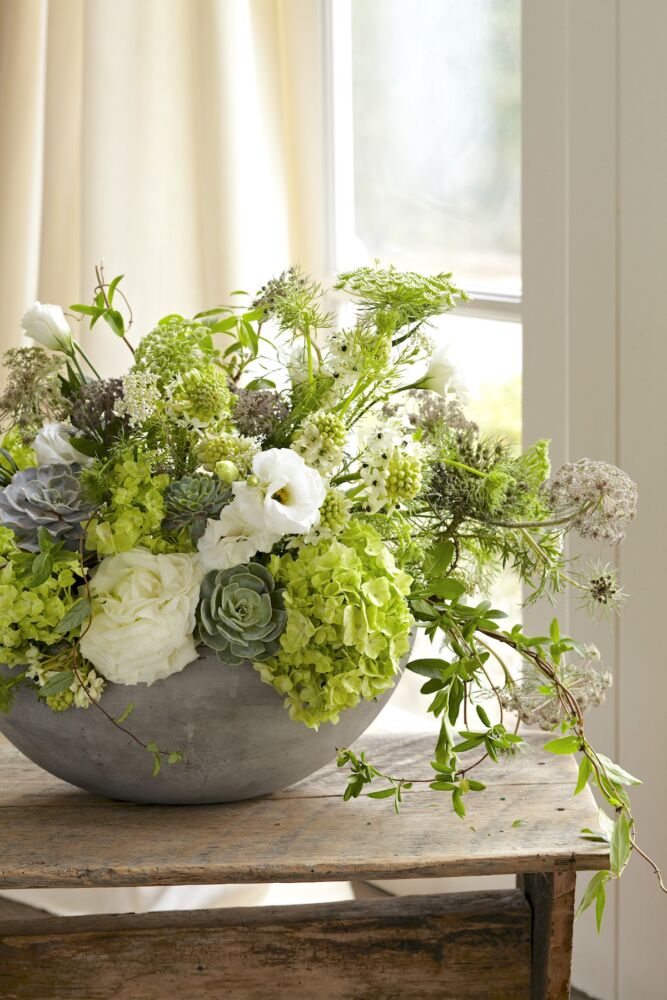 Green and white arrangement of hydrangeas, succulents, white roses, lisianthus, honeysuckle vine, and wildflowers