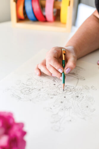 Hand sketching a floral arrangement with pencil.