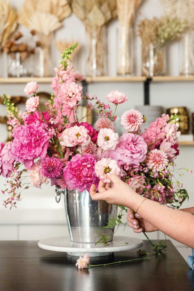 Adding tulips and dahlias to pink flower arrangement.