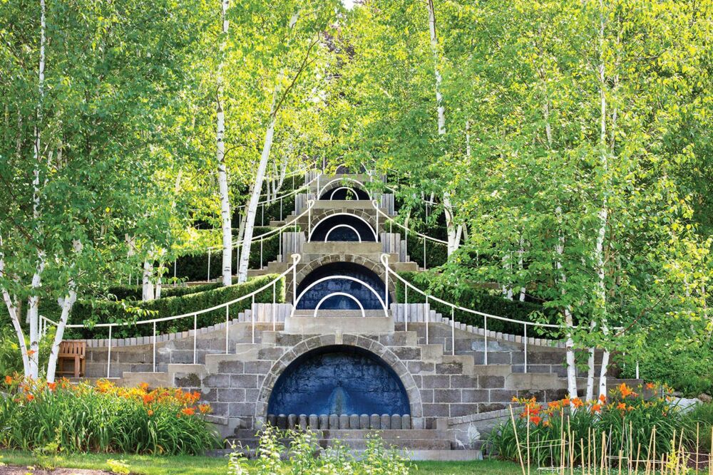Fletcher Steele's iconic Blue Steps at Naumkeag with bright orange daylilies blooming at bottom, and white-barked birches planted on each level.