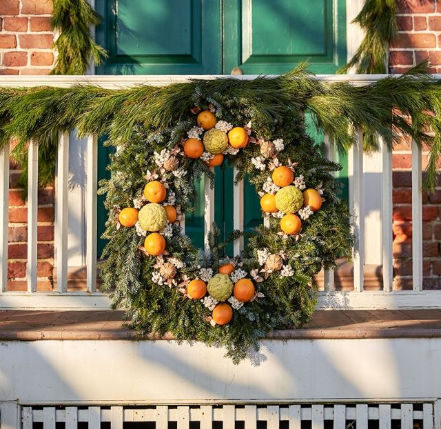 Orange and yellow citrus fruit hang on one of the Christmas wreaths of Williamburg.