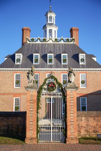 Governor's Palace Colonial Williamsburg decorated for Christmas with a wreath and swag of greenery over the gate, and wreaths on the windows.