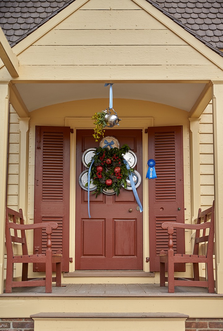 Silver plates surround a green wreath on a rusty red door.