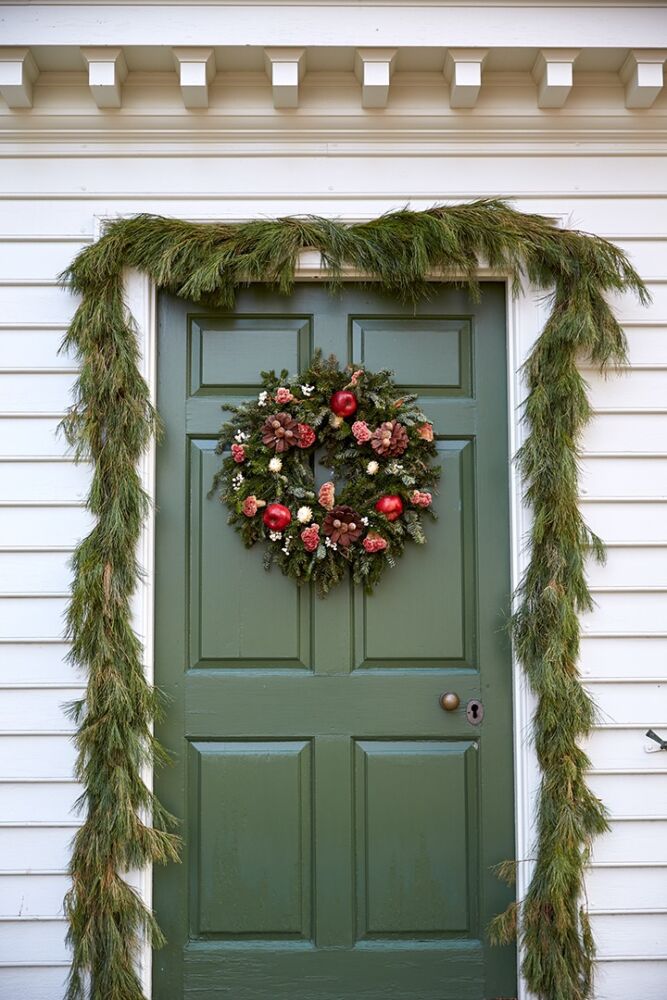 Pinecones shaped like flowers cover an evergreen wreath.