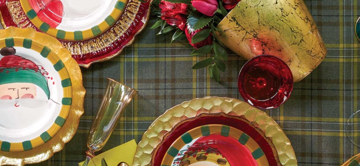 Christmas table setting with Santa Claus plates on a plaid tablecloth.