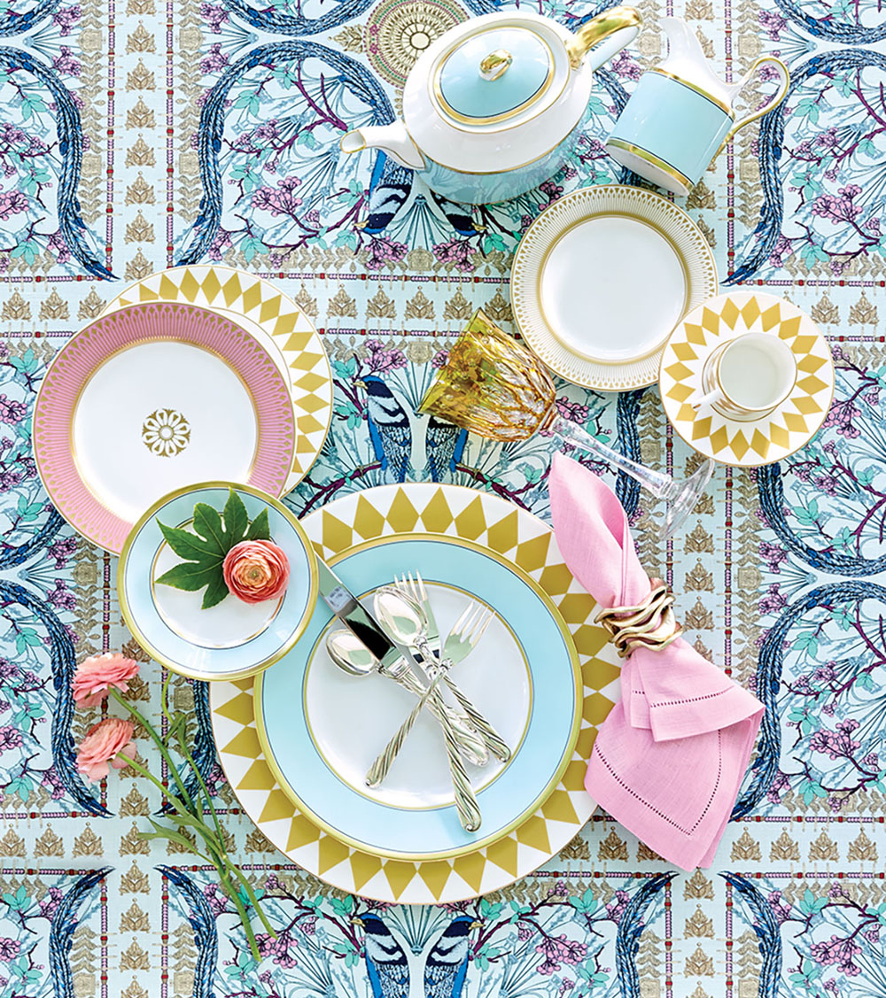 Spring table setting with shades of blue and pink are elevated by the symmetry of gold harlequin china sitting atop a fetching lyrebird pattern