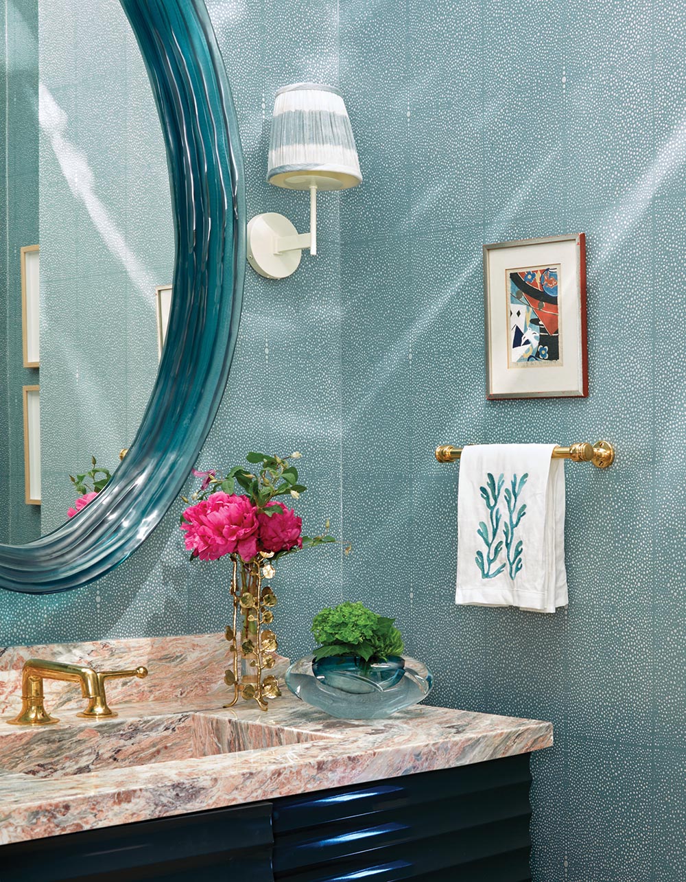 Two small flower arrangements atop pink-veined marble countertop in Nellie Howard Ossi designed powder room.