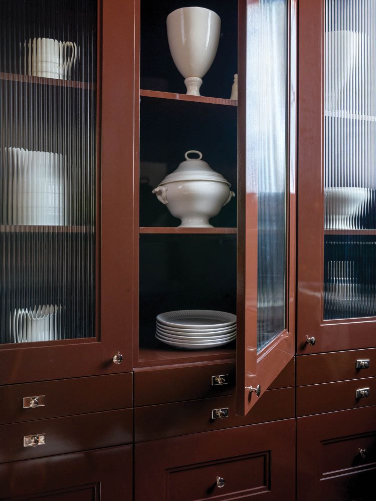 A mahogany cabinet holds white serveware.