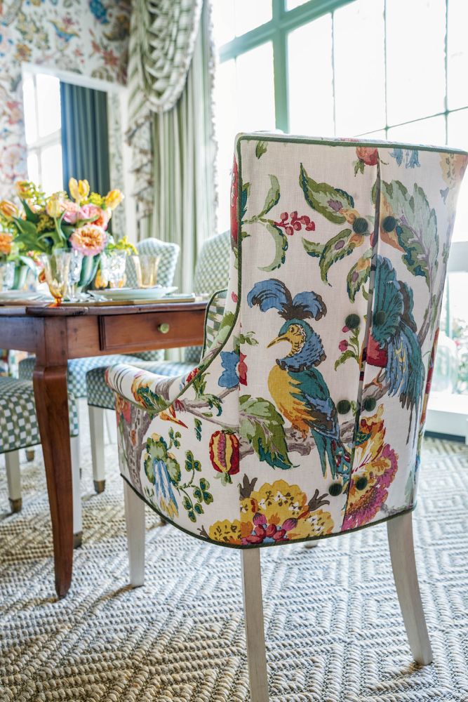 An upholstered chair has a floral pattern and buttons on the back.