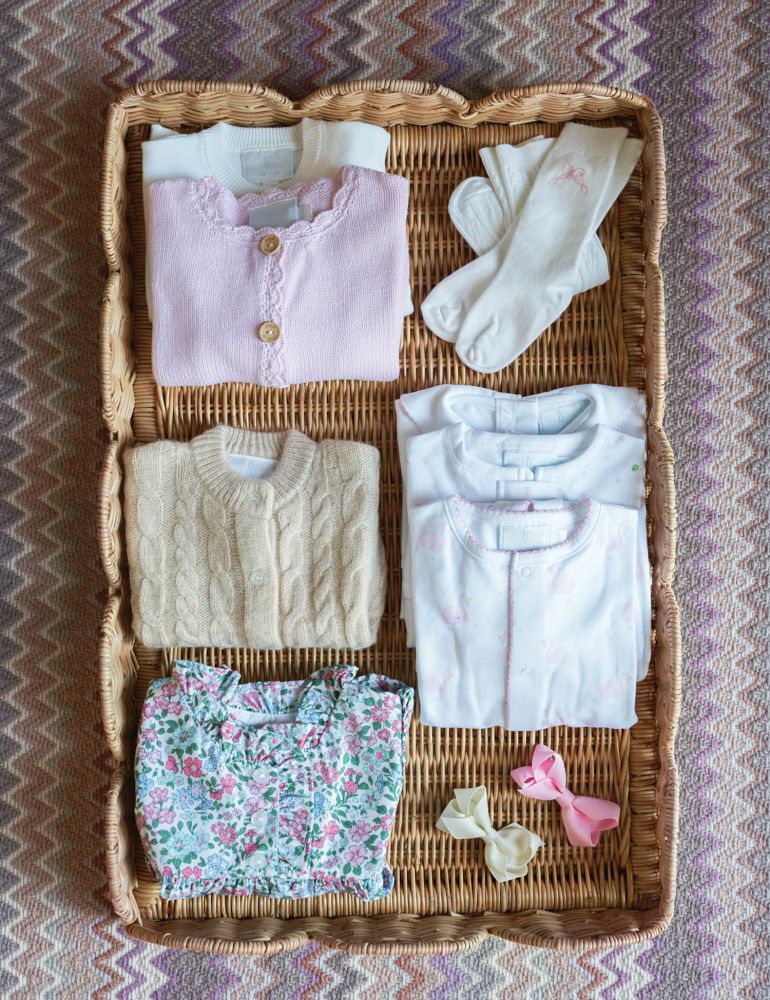 Little girl clothing is neatly folded in a rattan basket.