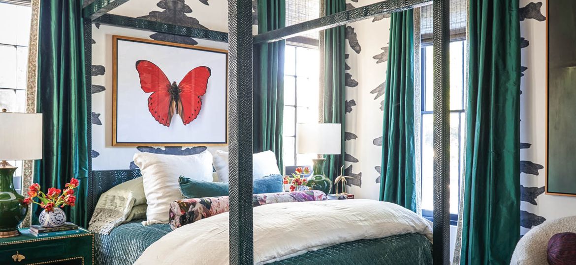 A butterfly painting hangs over a black and teal bed in a room with zebra wallpaper.