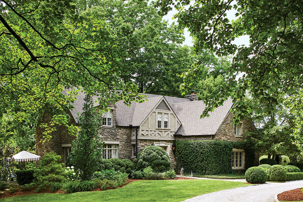 English Tudor exterior of landscape architect Gavin Duke's home, surrounded by lush trees, lawn, and landscaping