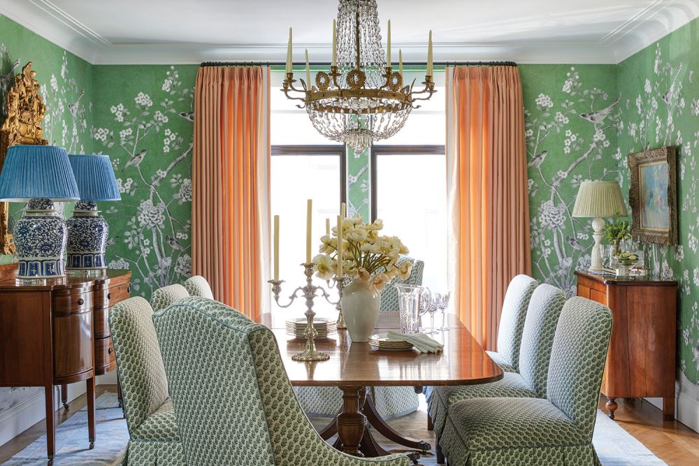 Green wallpaper with florals and pink curtains in a dining room.