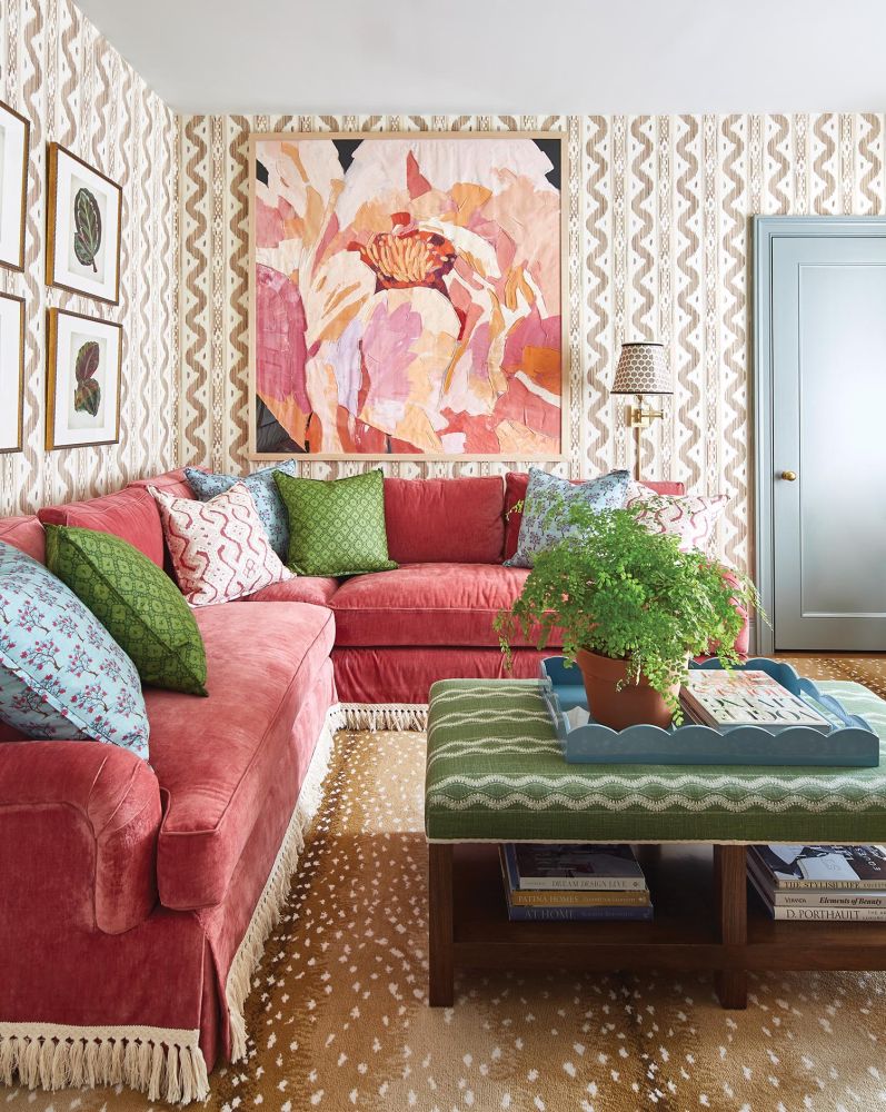 A pink velvet couch sits in a wallpapered living room.