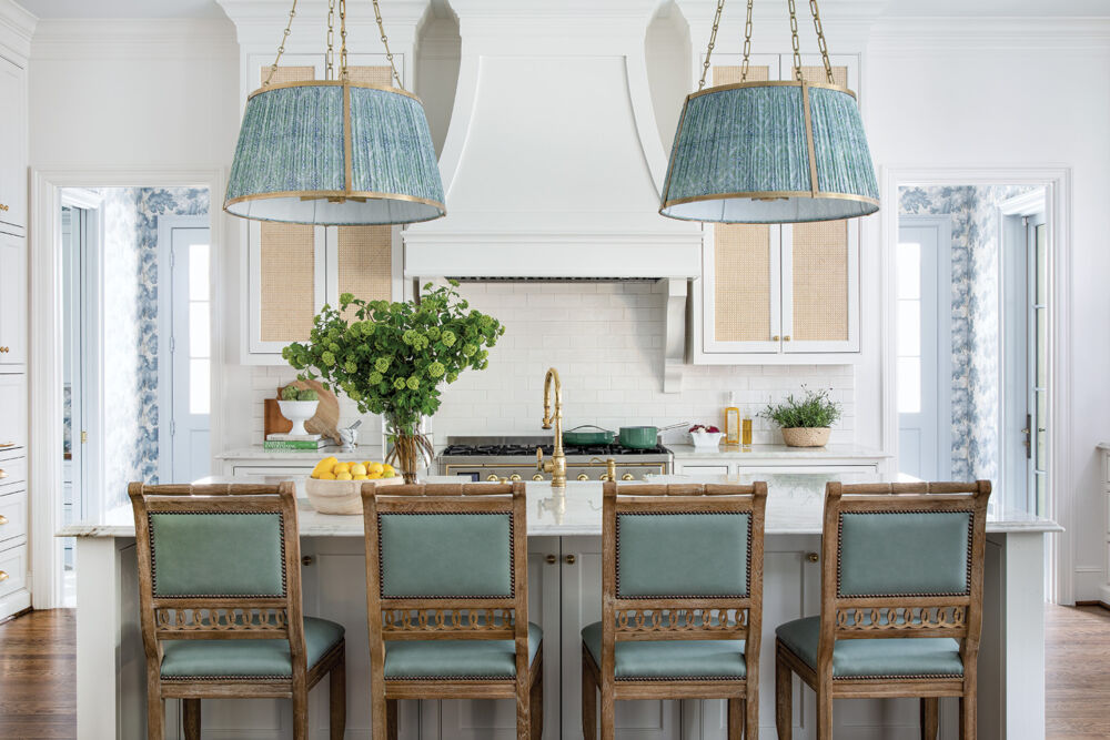 A white kitchen gleams with sea foam bar stools and ceiling lamps.