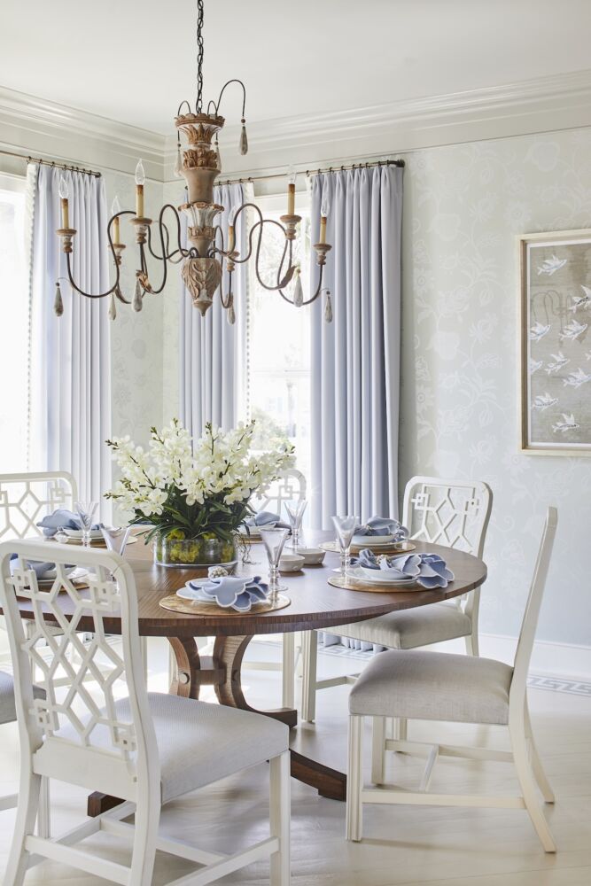 Dining room with Theodore Alexander table, Century chairs covered in Pierre Frey fabric, clear glass dish of white flowering orchids at center of table.