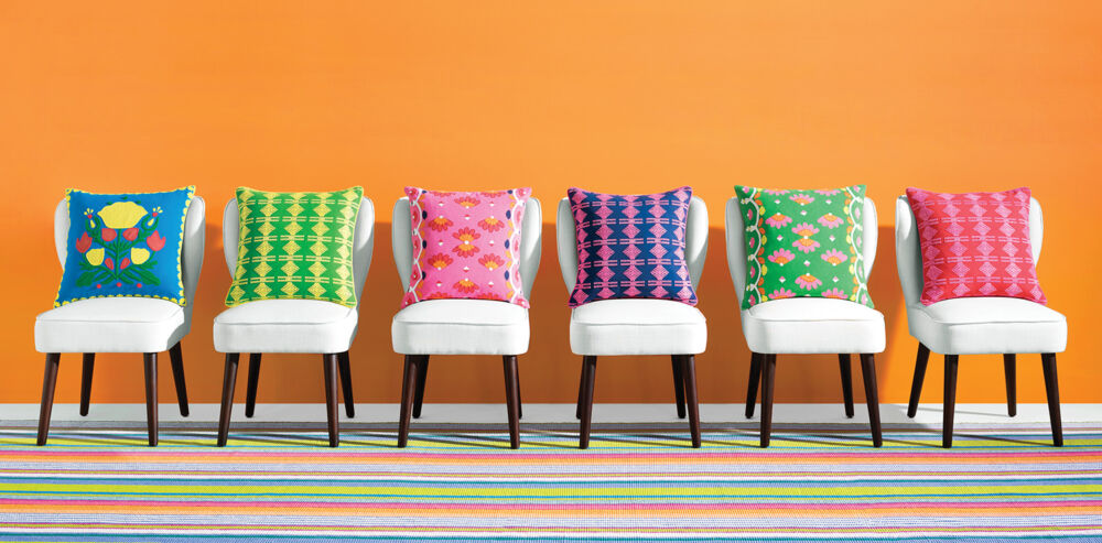 White chairs lined in a row carry bright pillows of every color.