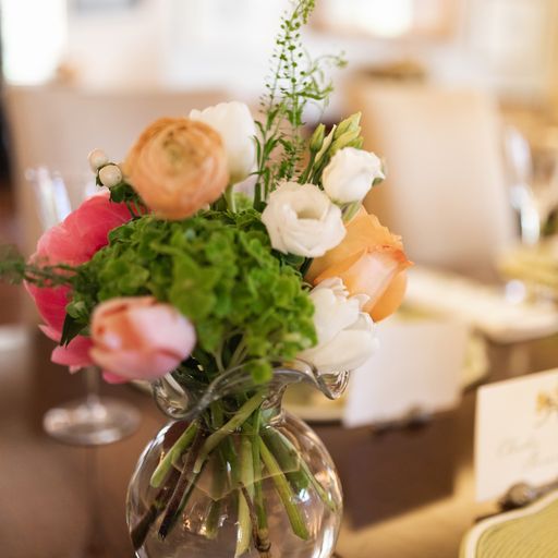 A small bouquet of greenery, white, pink, and orange peonies sit in a Vietri vase.