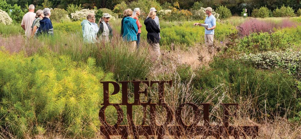 Visitors stand in a meadow full of prairie dropseed and a sign that says Piet Oudolf Meadow.