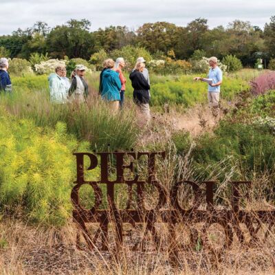 Visitors stand in a meadow full of prairie dropseed and a sign that says Piet Oudolf Meadow.