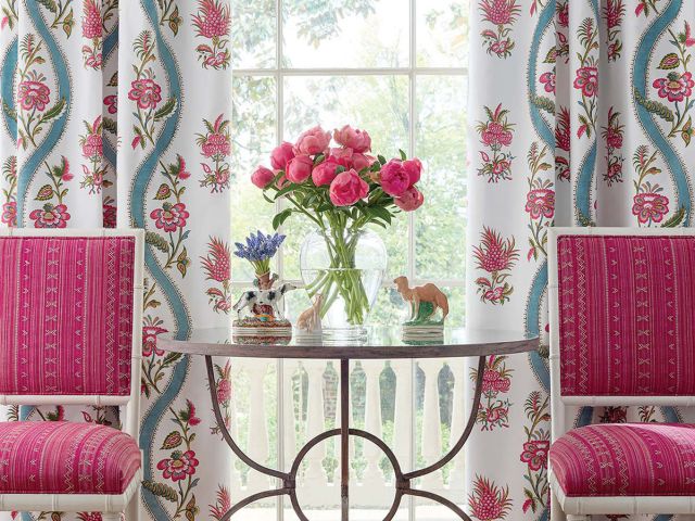 Floral curtains behind hot pink chairs.