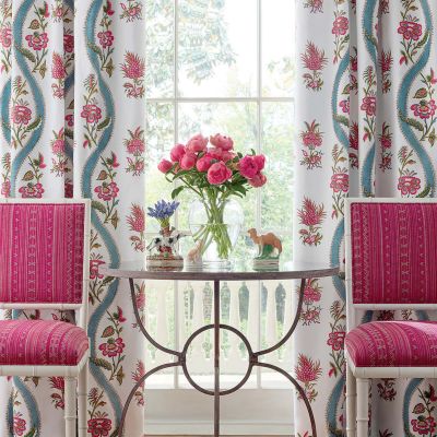 Floral curtains behind hot pink chairs.
