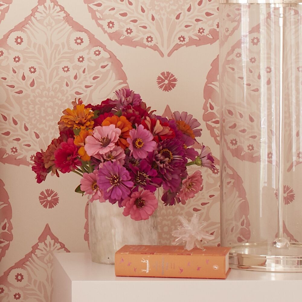 Vase of pink and coral zinnias on a bedside table