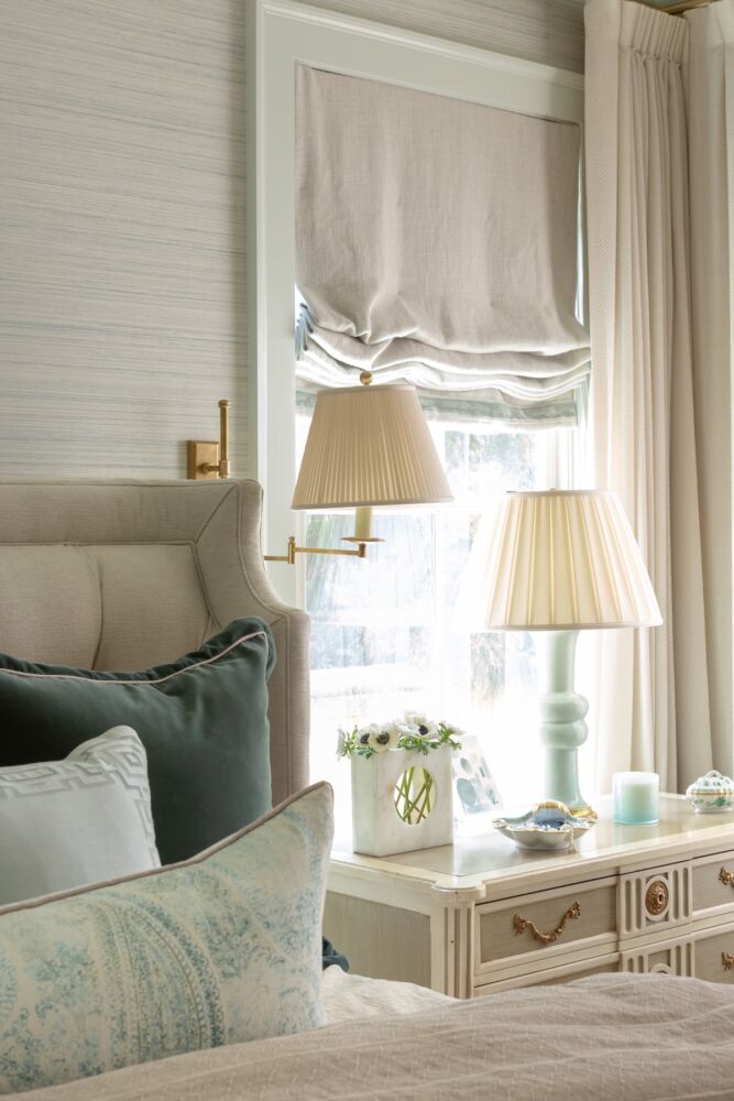 In a traditional bedroom dressed in pretty neutrals, Nashville designer Blaire Murfree included a brass swing arm lamp with a pleated shade with a pale blue table lamp.