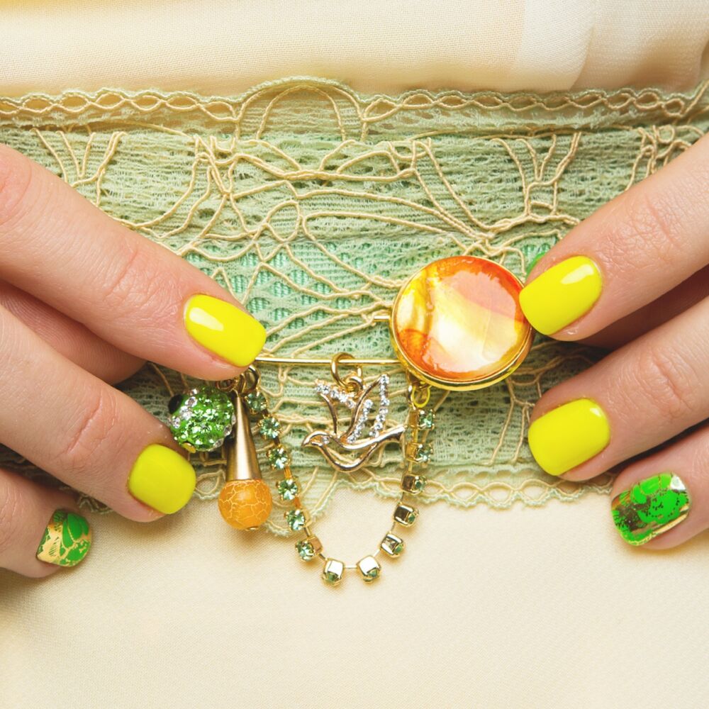 Pin with orange and yellow stone, charms, chain of green stones on green lace belt.