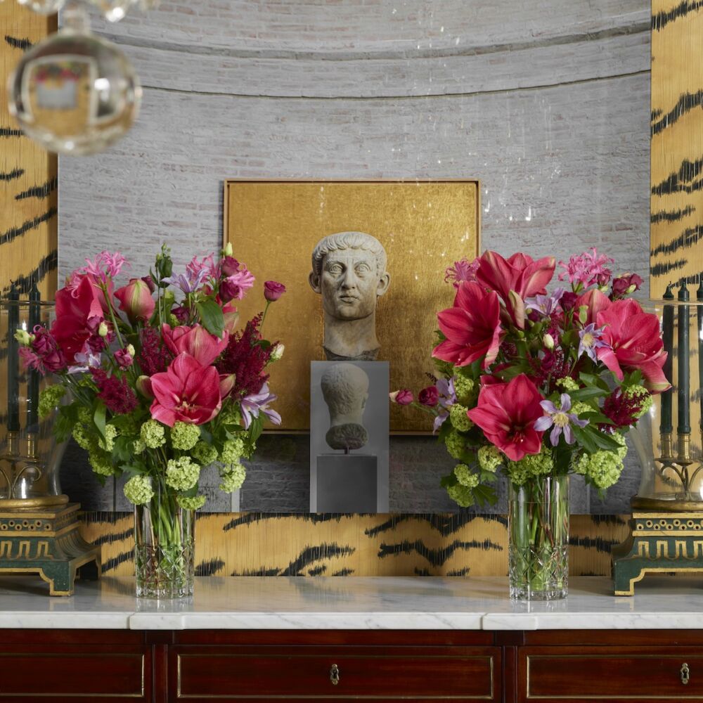 Flower arrangements on dining room sideboard with photograph of a roman bust behind them