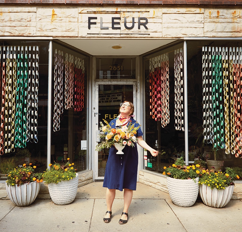 Kelly Marie Thompson stands outside her shop, Fleur, holding her flower arrangement and looking at the sky.