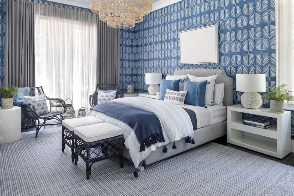 A large-scale tiered pendant light with bedside table lamps in a blue-infused bedroom.