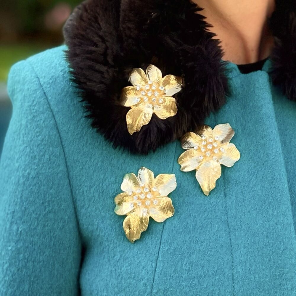 Three golden floral brooches on a wool turquoise jacket.
