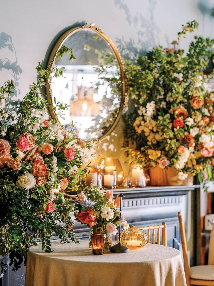 Organic flower arrangements sit next to a candlelit table.