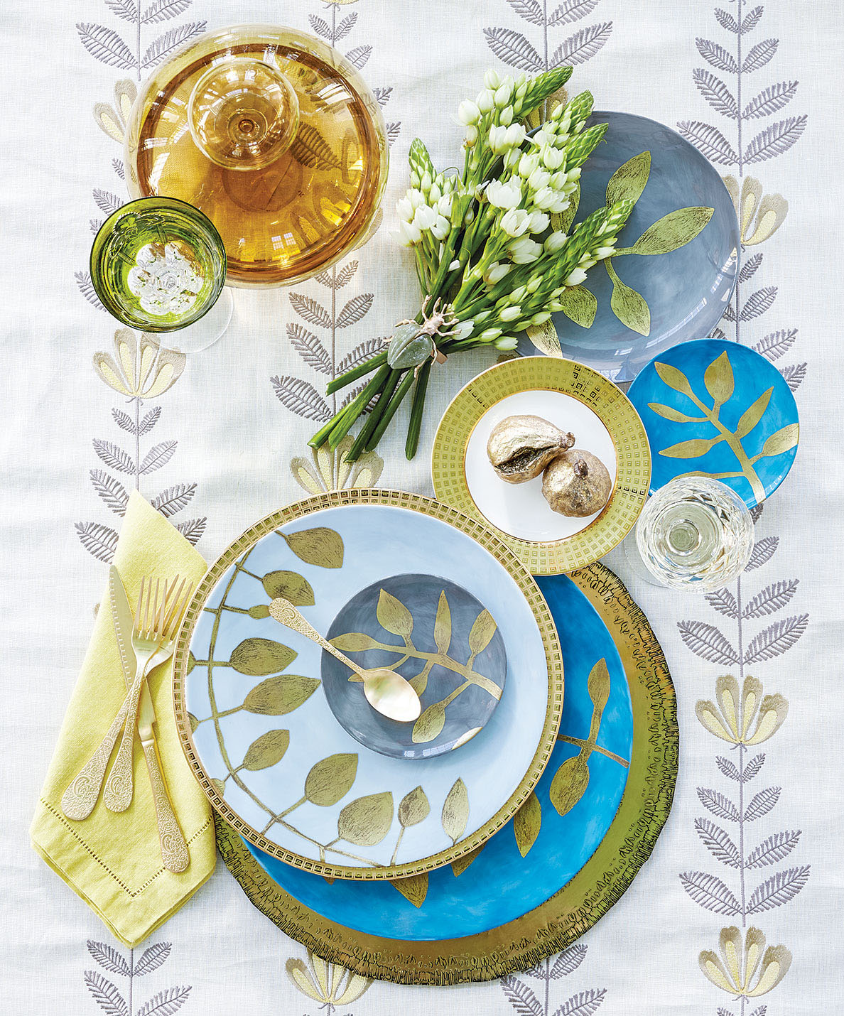 Tablescape with calming repetition of eaves, on both the china and the tablecloth, and a burst of blues and yellow-gold