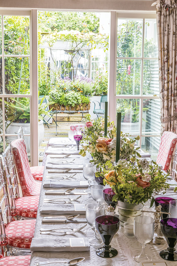A flower-filled table setting in Nina Campbell's dining room. The french doors are open, leading to the garden terrace beyond