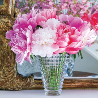 Pink peonies in Baccarat's Crystal Eye Vase. In the background stands an ornate gilt frame mirror