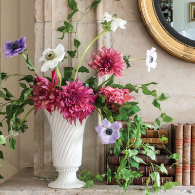 Loose, garden inspired arrangement of dark pink dahlias, white and light purple anemones, and trailing vines by floral designer Mieke ten Have in a white pottery vase