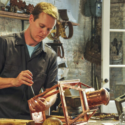 a craftsman at Bevolo works on a copper gas lantern