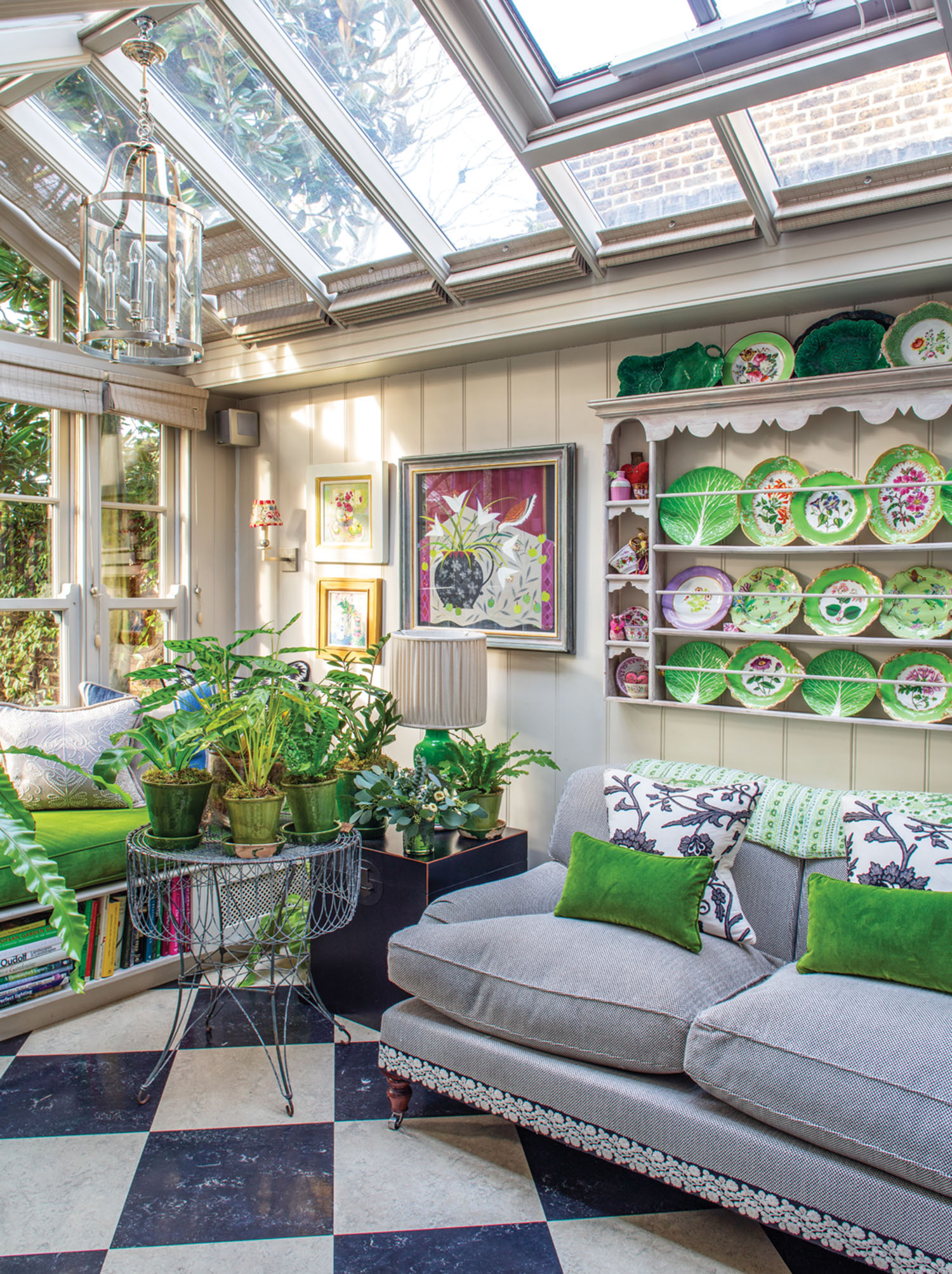 BUTTER WAKEFIELD HOUSE, LONDON: CHRISTMAS - THE GARDEN ROOM. GLASS CONSERVATORY JUST OFF THE KITCHEN WITH SOFA AND BUTTER'S CHINA PLATES DISPLAYED ON PLATE RACK. FERNS