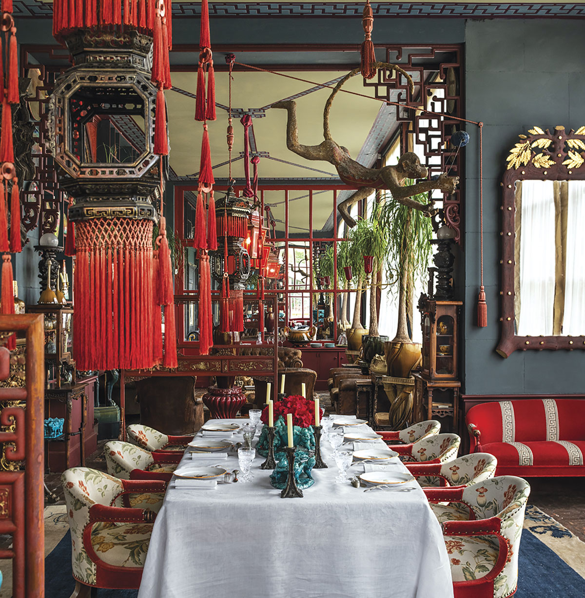 A table for 6 in a Chinese-inspired dining room. The primary color is dusty blue with bright red accents. From the pages of Be My Guest by Pierre Sauvage and Olivia Roland